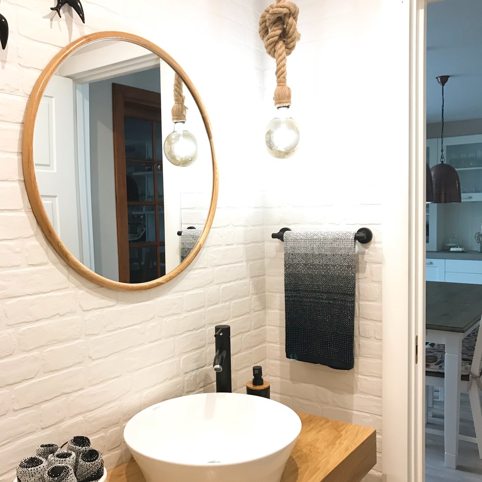 Cette image montre un petit WC et toilettes nordique en bois brun avec un placard sans porte, WC à poser, un carrelage blanc, des carreaux de céramique, un mur multicolore, parquet clair, une vasque et un plan de toilette en bois.