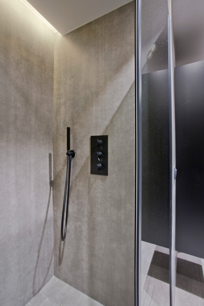 Photo of a medium sized contemporary cloakroom in Other with flat-panel cabinets, black cabinets, a wall mounted toilet, grey tiles, ceramic tiles, grey walls, ceramic flooring, a vessel sink, glass worktops, grey floors and grey worktops.