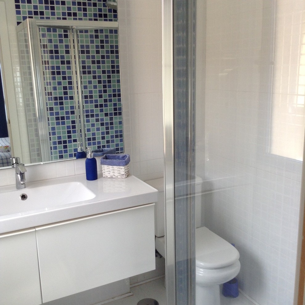 Esempio di un piccolo bagno di servizio mediterraneo con WC sospeso, piastrelle blu, piastrelle a mosaico, pareti multicolore, pavimento con piastrelle in ceramica e pavimento bianco