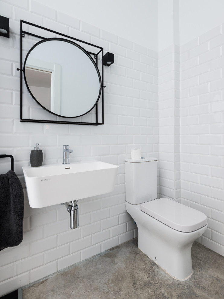 Idée de décoration pour un WC et toilettes nordique avec des portes de placard blanches, un carrelage blanc et sol en béton ciré.