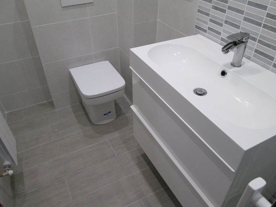 Ispirazione per un piccolo bagno di servizio minimal con ante lisce, ante bianche, WC monopezzo, pareti grigie e lavabo integrato