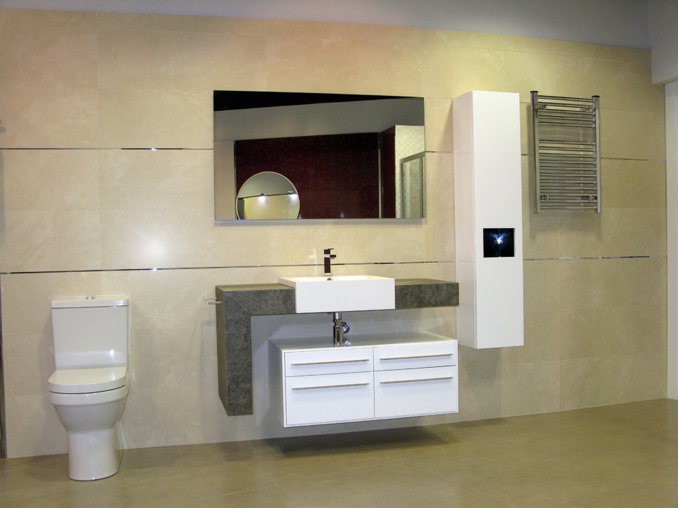 Klassisk inredning av ett stort toalett, med släta luckor, vita skåp, en toalettstol med separat cisternkåpa, beige väggar och ett nedsänkt handfat