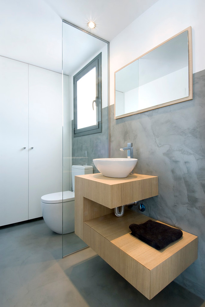 Idéer för små funkis beige toaletter, med släta luckor, skåp i ljust trä, grå väggar, betonggolv, ett fristående handfat, träbänkskiva och grått golv