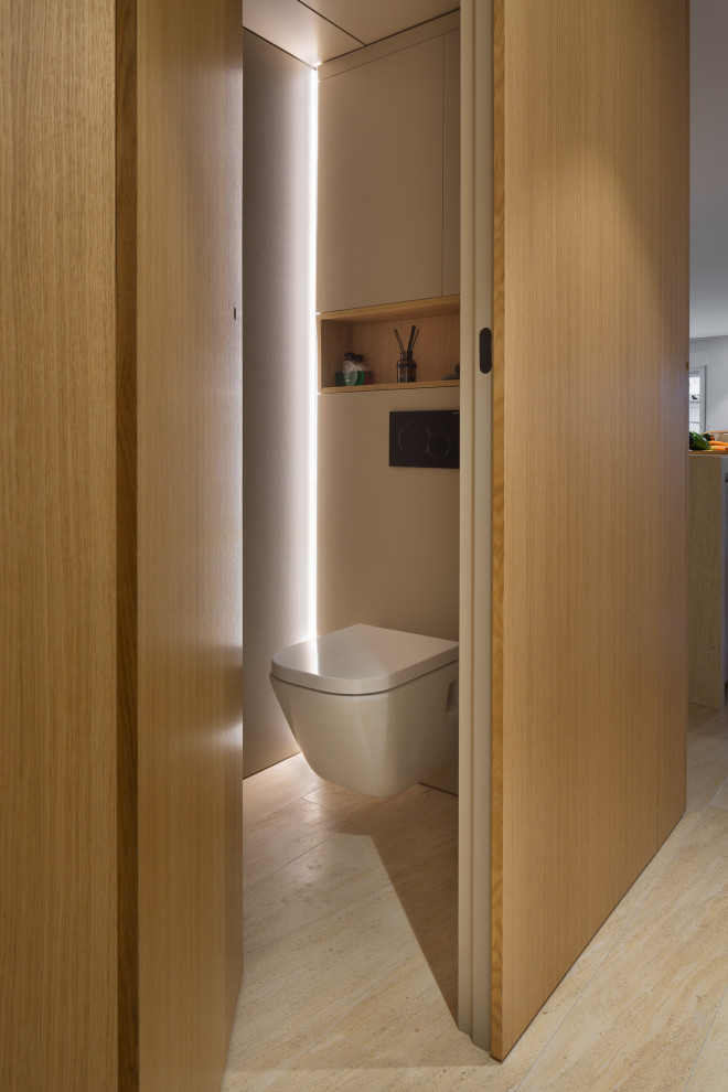 Стильный дизайн: туалет в стиле модернизм с коричневыми фасадами, полом из известняка, монолитной раковиной, столешницей из известняка, коричневым полом и встроенной тумбой - последний тренд