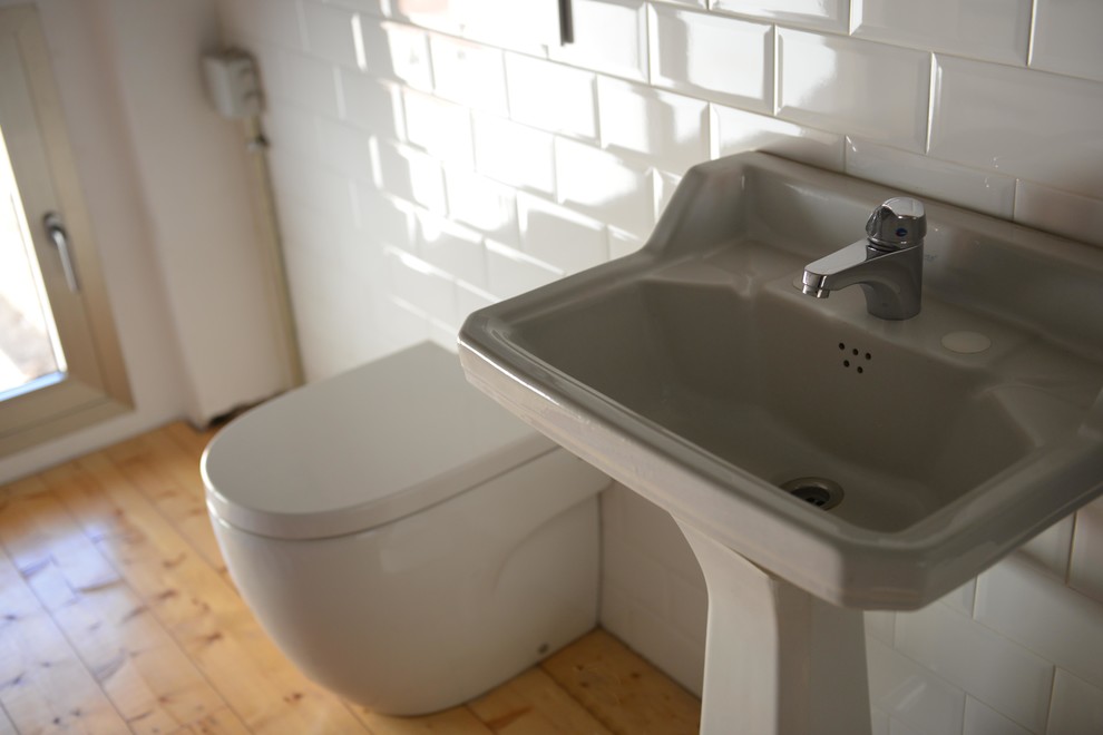 Cette photo montre un petit WC et toilettes chic avec WC à poser, un mur blanc, un sol en bois brun et un lavabo de ferme.