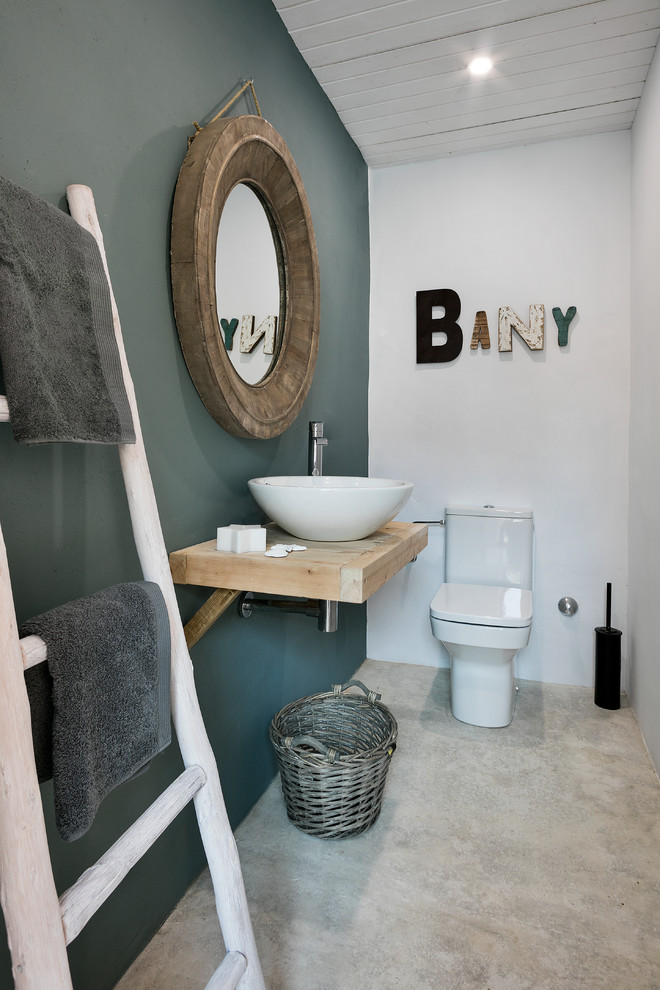 Kleine Rustikale Gästetoilette mit bunten Wänden, Betonboden, Aufsatzwaschbecken, Waschtisch aus Holz, grauem Boden und beiger Waschtischplatte in Barcelona