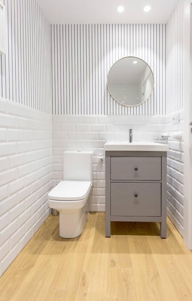 This is an example of a scandi cloakroom in Other with freestanding cabinets, grey cabinets, white tiles, metro tiles, multi-coloured walls and light hardwood flooring.