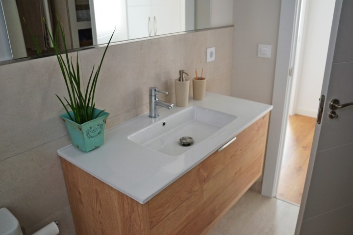 Cette photo montre un WC et toilettes scandinave en bois clair de taille moyenne avec un placard à porte plane, WC séparés, un mur beige et un lavabo intégré.