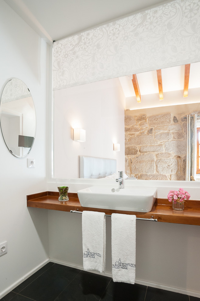 Kleine Landhausstil Gästetoilette mit braunem Holzboden, weißer Wandfarbe, Aufsatzwaschbecken und Waschtisch aus Holz in Sonstige