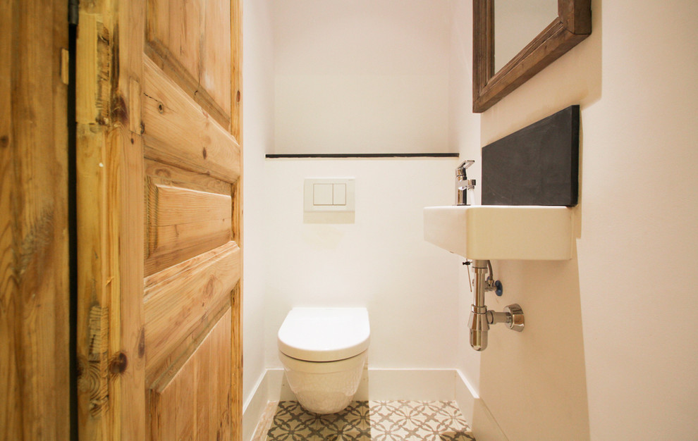 Immagine di un piccolo bagno di servizio minimal con WC sospeso, pareti bianche, pavimento con piastrelle in ceramica e lavabo sospeso