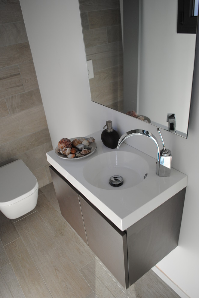 This is an example of a small contemporary cloakroom in Barcelona with flat-panel cabinets, white walls, light hardwood flooring, a wall-mounted sink and a wall mounted toilet.