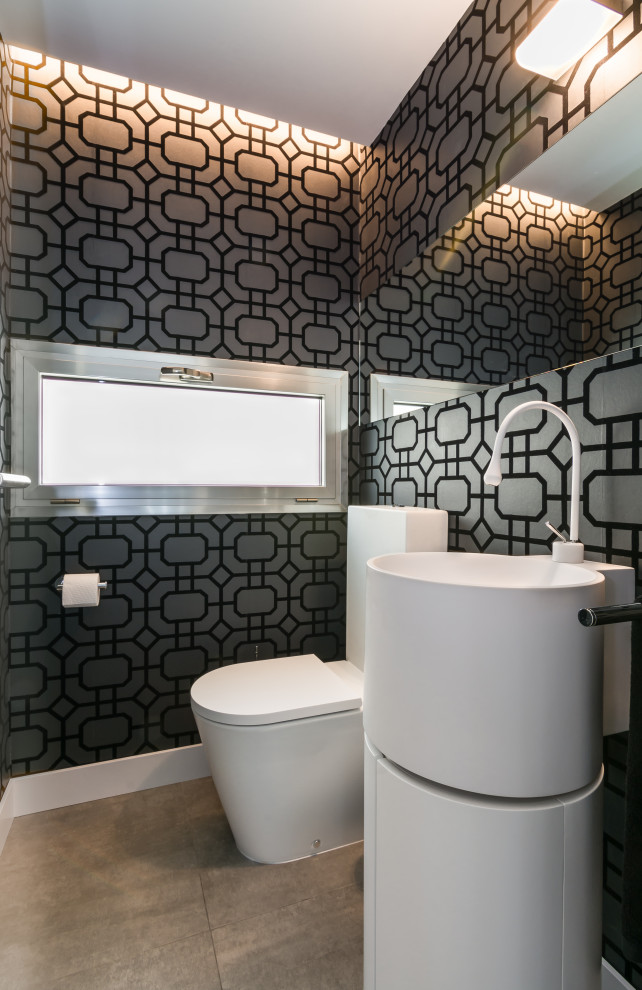 Пример оригинального дизайна: туалет среднего размера в современном стиле с унитазом-моноблоком, черной плиткой, серой плиткой, стеклянной плиткой, полом из керамогранита, монолитной раковиной и серым полом