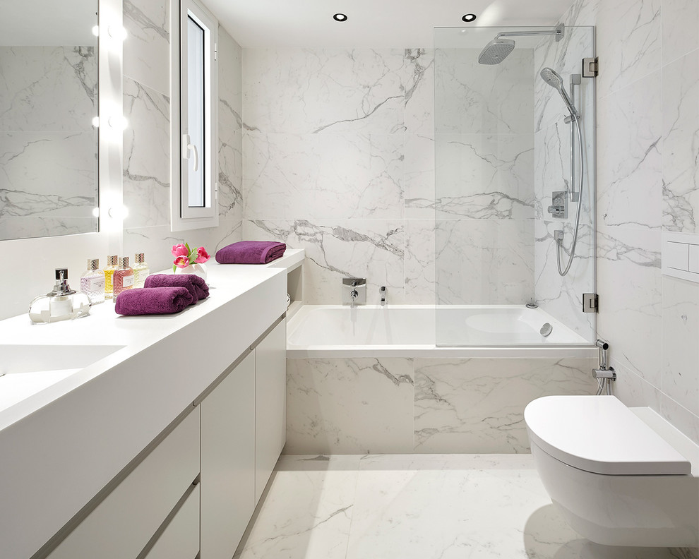 Modelo de cuarto de baño contemporáneo con armarios con paneles lisos, puertas de armario blancas, baldosas y/o azulejos blancos, paredes blancas, lavabo integrado, suelo blanco, encimeras blancas y sanitario de pared