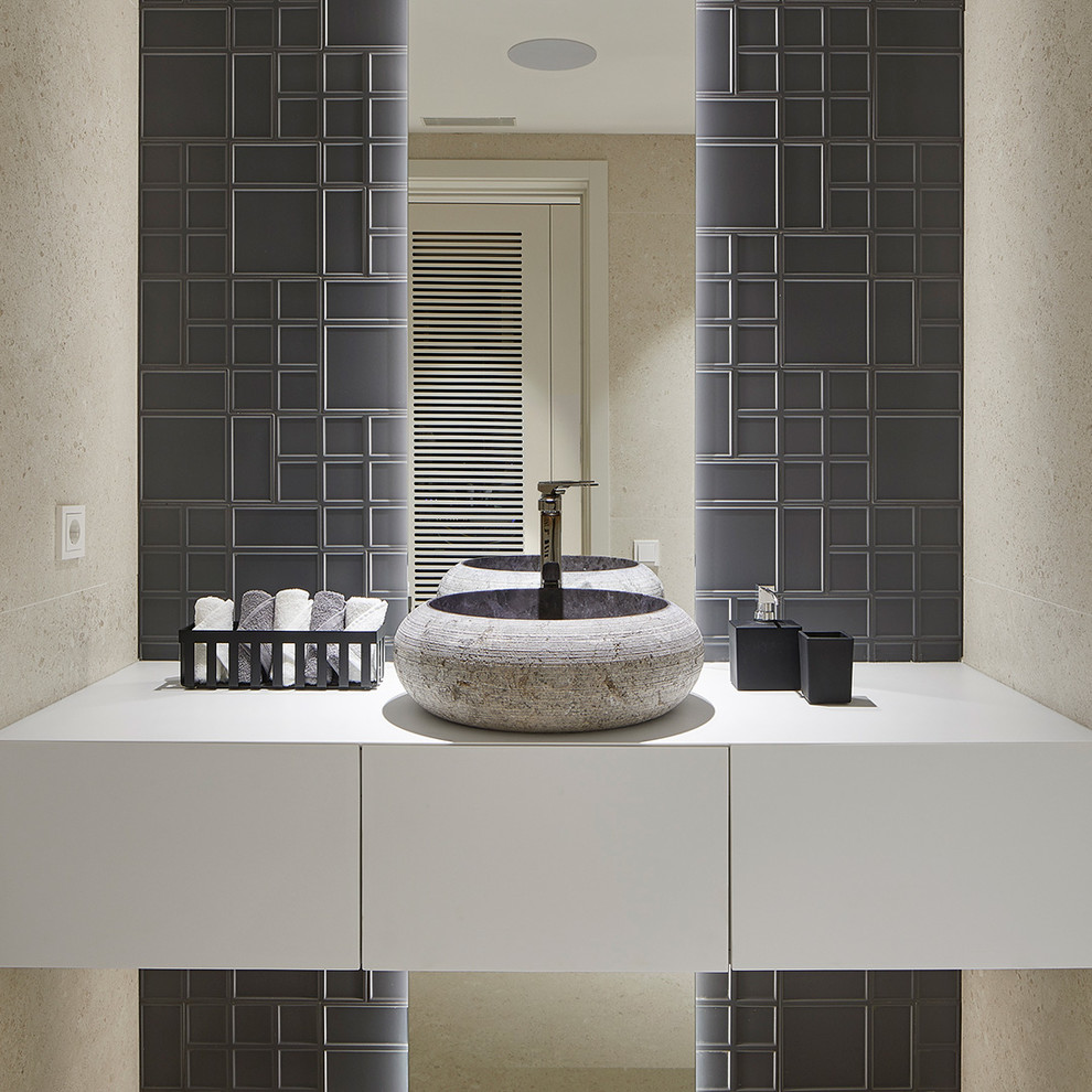 Пример оригинального дизайна: туалет в современном стиле с плоскими фасадами, белыми фасадами, бежевой плиткой, серой плиткой, бежевыми стенами, настольной раковиной и белой столешницей
