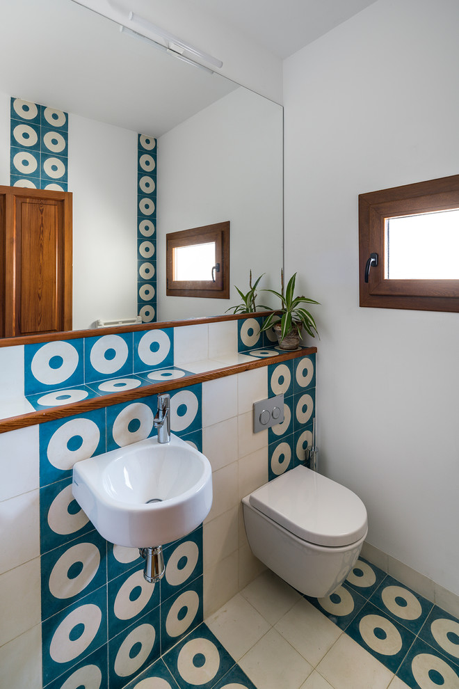 Idéer för små funkis toaletter, med en vägghängd toalettstol, blå kakel, vit kakel, vita väggar, ett väggmonterat handfat och keramikplattor