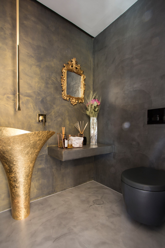 Bild på ett litet eklektiskt toalett, med en vägghängd toalettstol, grå väggar, betonggolv, ett piedestal handfat och grått golv