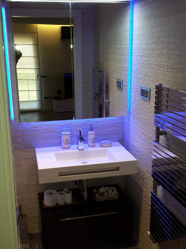 Immagine di un piccolo bagno di servizio minimalista con ante di vetro, piastrelle beige, piastrelle in gres porcellanato, pareti beige, pavimento in gres porcellanato, lavabo sospeso e top in superficie solida