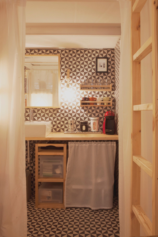 Modelo de aseo escandinavo de tamaño medio con armarios abiertos, puertas de armario de madera clara, paredes multicolor, suelo de baldosas de cerámica, lavabo sobreencimera y encimera de madera