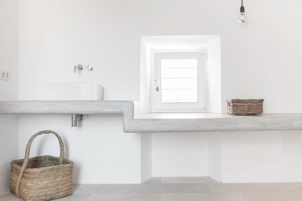 На фото: маленький туалет в средиземноморском стиле с настольной раковиной, белыми стенами, полом из травертина и столешницей из бетона для на участке и в саду