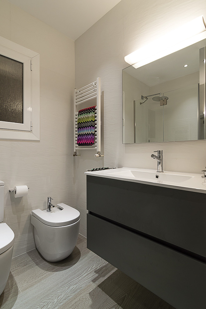 Kleine Moderne Gästetoilette mit weißen Fliesen, Keramikfliesen, weißer Wandfarbe, Keramikboden, integriertem Waschbecken und Bidet in Barcelona