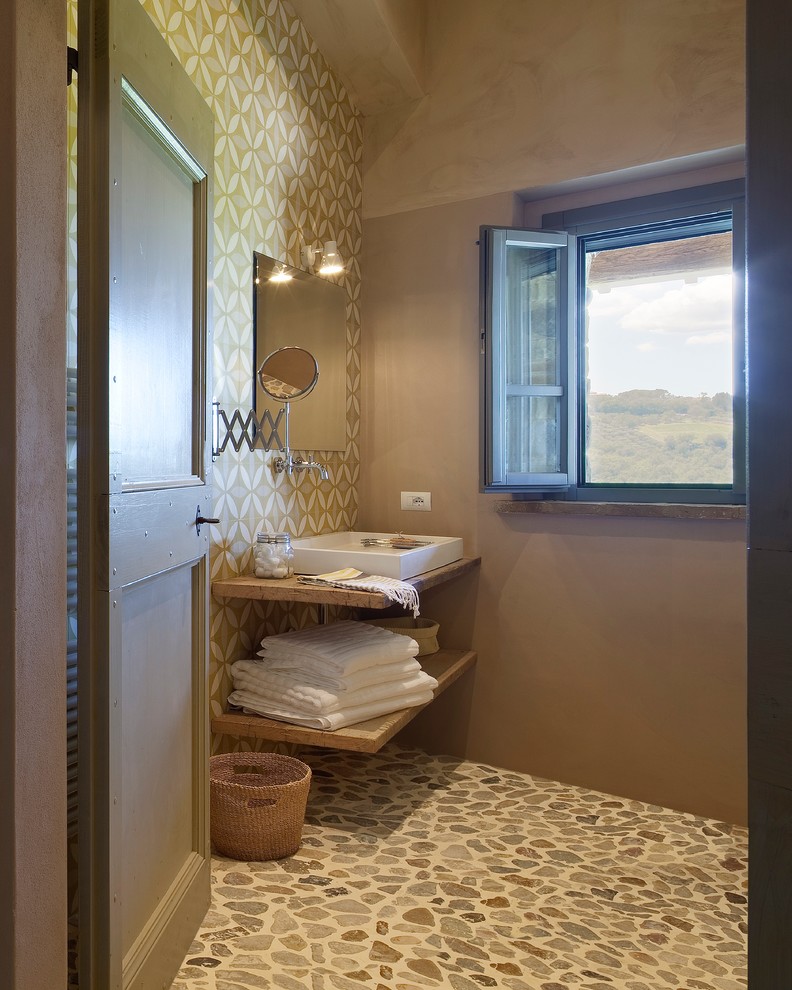 Exempel på ett litet klassiskt brun brunt toalett, med öppna hyllor, skåp i mellenmörkt trä, flerfärgade väggar, ett fristående handfat och träbänkskiva