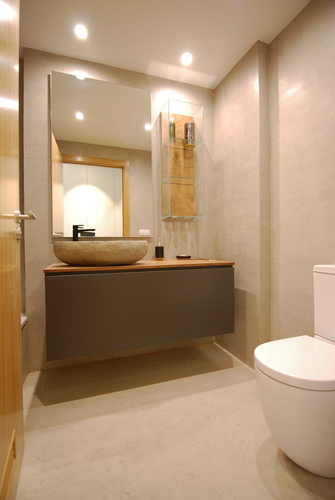 Idée de décoration pour un petit WC et toilettes minimaliste avec un mur gris, des portes de placard grises, sol en béton ciré, une vasque et un plan de toilette en bois.