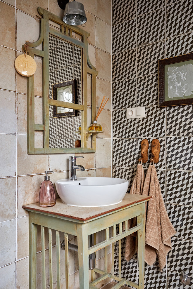 Photo of a small mediterranean cloakroom in Madrid with a vessel sink, freestanding cabinets, distressed cabinets, beige tiles, black and white tiles, wooden worktops and beige worktops.