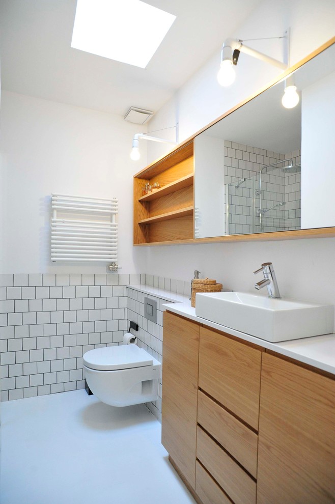 Aménagement d'un grand WC suspendu scandinave en bois brun avec un placard à porte plane, un mur blanc et une vasque.