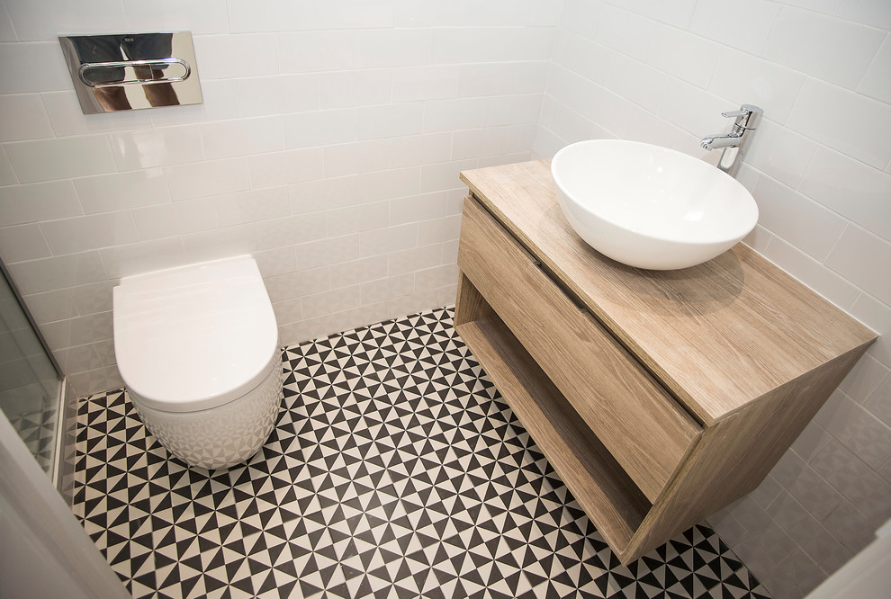 Cette photo montre un WC et toilettes moderne en bois brun de taille moyenne avec WC à poser, un carrelage blanc, un mur blanc, une vasque et un sol multicolore.