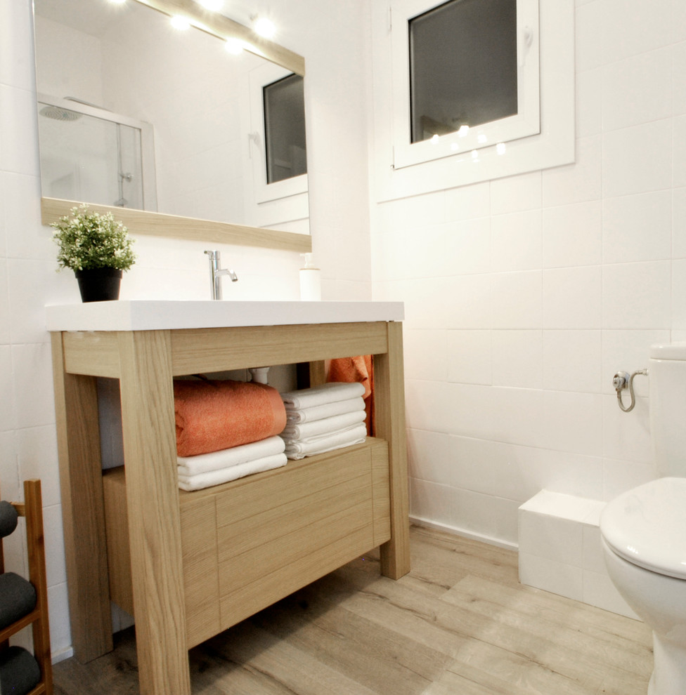 Photo of a small classic cloakroom in Madrid with open cabinets, a two-piece toilet, white walls, medium hardwood flooring and an integrated sink.
