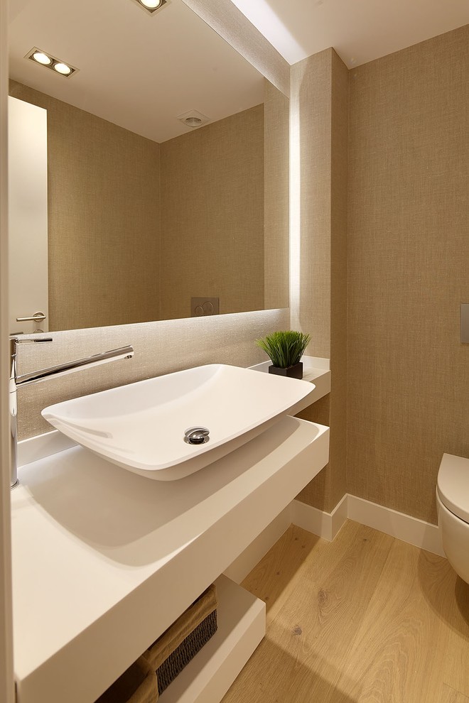 Cette photo montre un petit WC suspendu méditerranéen avec un placard sans porte, un mur beige, un sol en bois brun et une vasque.