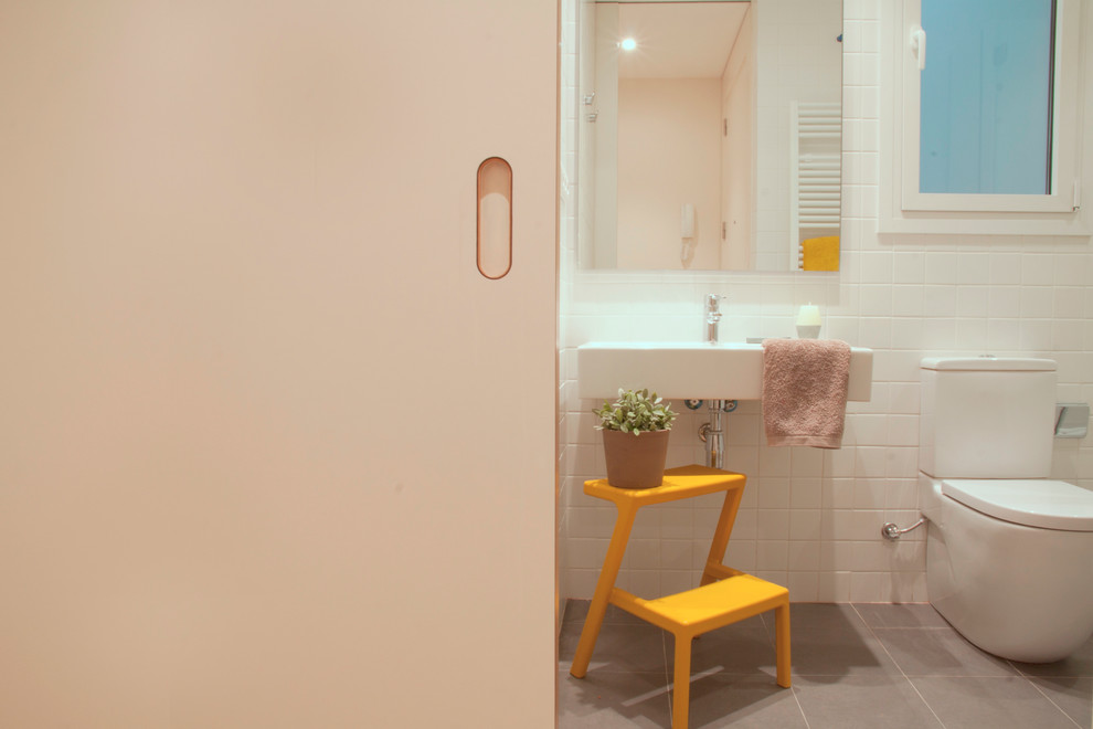 Réalisation d'un petit WC et toilettes nordique avec WC séparés, un carrelage blanc, des carreaux de céramique, un mur blanc, un sol en carrelage de céramique et un lavabo suspendu.