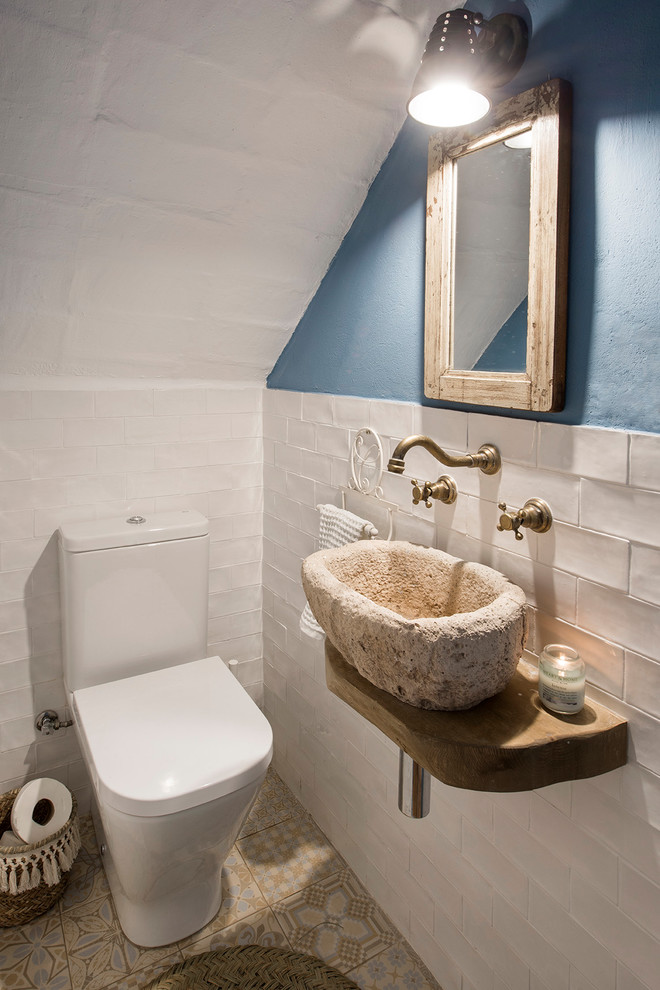 Imagen de aseo mediterráneo pequeño con sanitario de dos piezas, lavabo sobreencimera, paredes azules, suelo de azulejos de cemento y suelo multicolor
