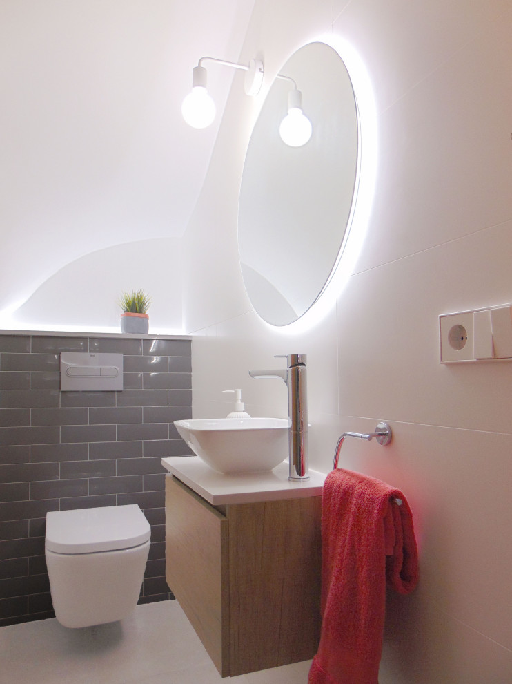 Inredning av ett modernt litet vit vitt toalett, med skåp i mellenmörkt trä, en vägghängd toalettstol, vit kakel, keramikplattor, grå väggar, klinkergolv i keramik, ett fristående handfat, bänkskiva i täljsten och grått golv