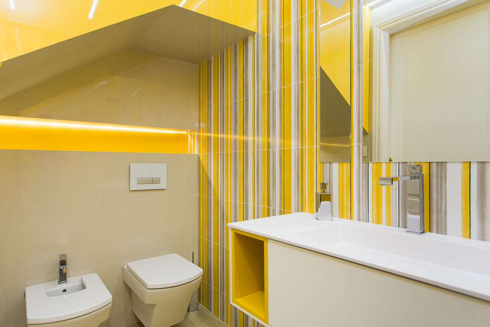 Aménagement d'un petit WC et toilettes contemporain avec un placard à porte plane, des portes de placard blanches, un bidet, un mur jaune et un lavabo intégré.
