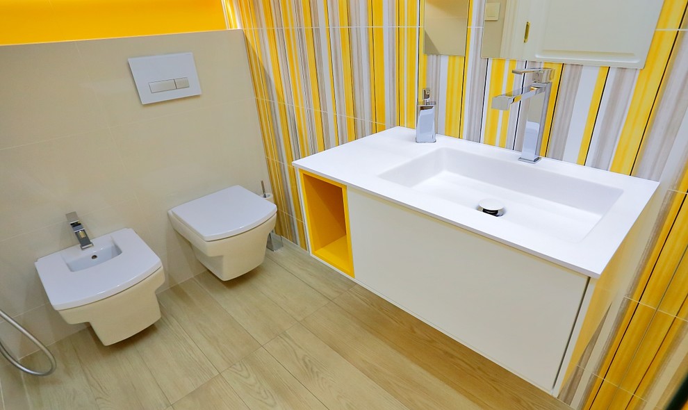 Diseño de aseo actual pequeño con armarios con paneles lisos, puertas de armario blancas, bidé, paredes amarillas y lavabo integrado