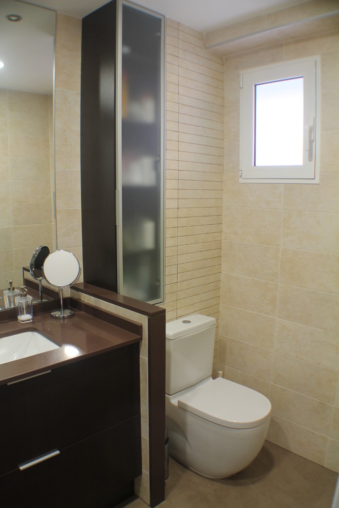 Immagine di un piccolo bagno di servizio contemporaneo con ante lisce, ante in legno bruno, WC a due pezzi e lavabo integrato