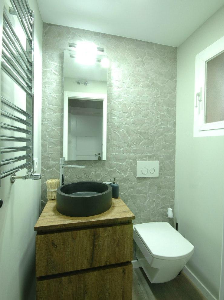 Kleine Klassische Gästetoilette mit verzierten Schränken, hellbraunen Holzschränken, Wandtoilette, bunten Wänden, Aufsatzwaschbecken und Waschtisch aus Holz in Madrid
