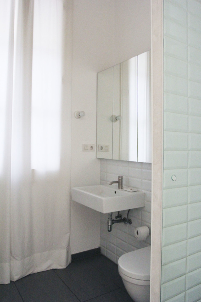 Photo of a small traditional cloakroom in Barcelona with a one-piece toilet, white walls and a wall-mounted sink.