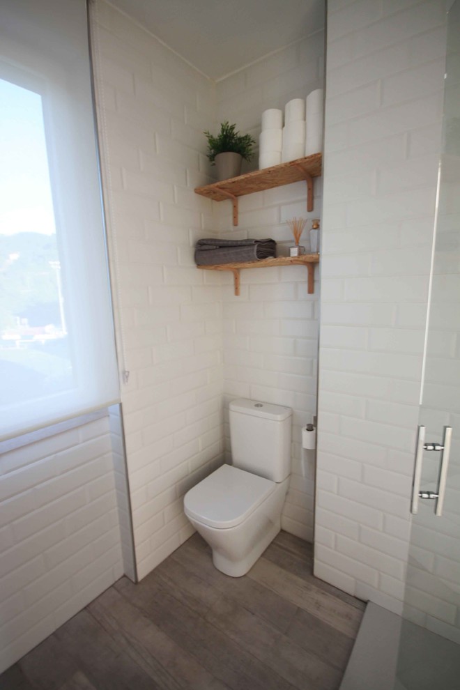 Idées déco pour un WC et toilettes scandinave de taille moyenne avec WC séparés, un carrelage blanc, un mur blanc et un sol en bois brun.
