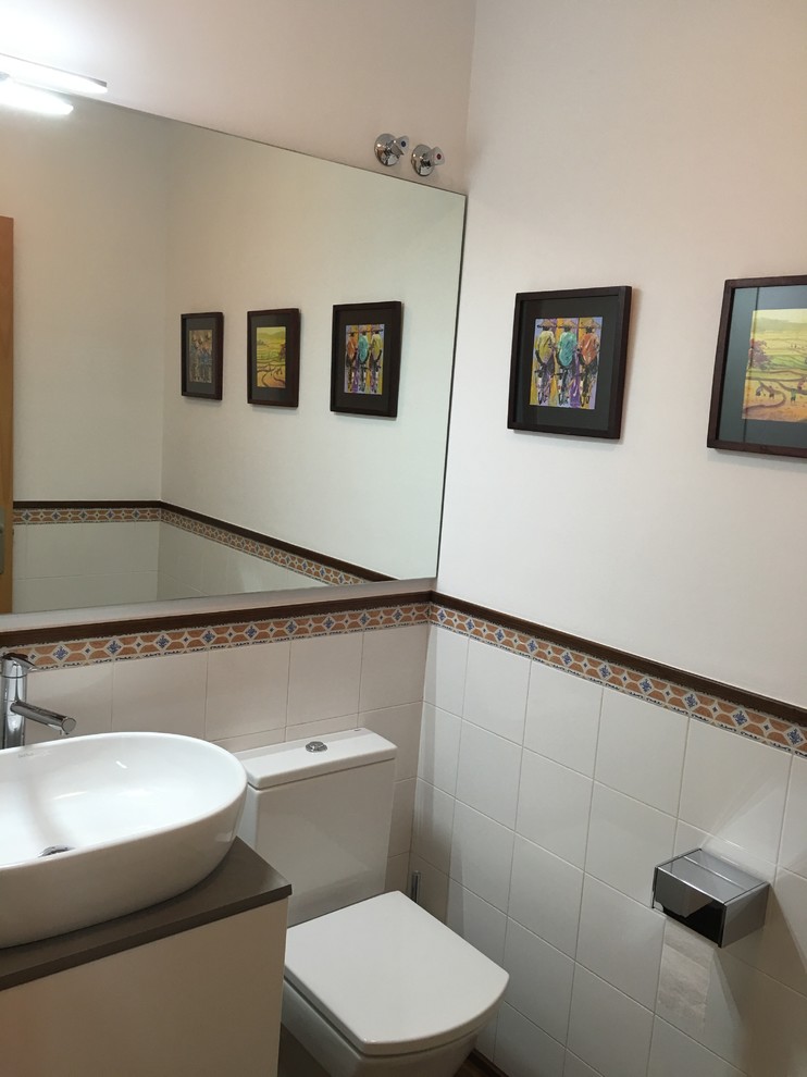 This is an example of a small scandinavian cloakroom in Other with freestanding cabinets, white cabinets, a one-piece toilet, white tiles, ceramic tiles, white walls, medium hardwood flooring, a vessel sink, terrazzo worktops and brown floors.