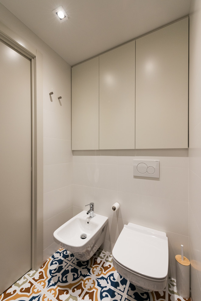 Idées déco pour un petit WC et toilettes contemporain avec un placard à porte plane, des portes de placard blanches, un bidet, un mur blanc et un sol en carrelage de céramique.