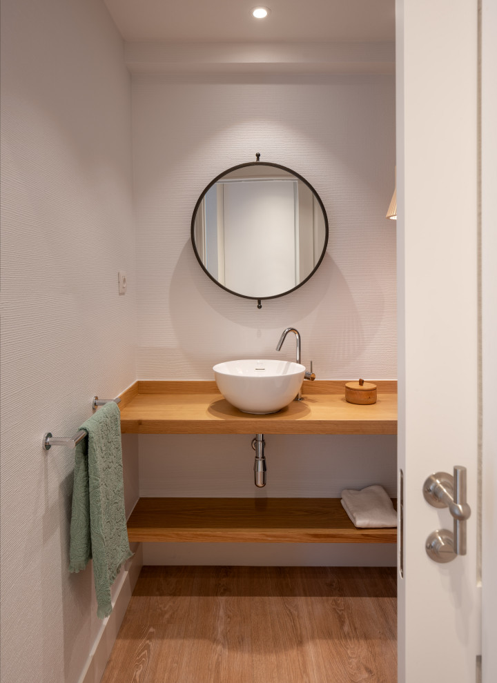 Idées déco pour un petit WC suspendu classique avec des portes de placard blanches, un carrelage beige, un mur blanc, sol en stratifié, une vasque, un plan de toilette en bois, un sol beige, un plan de toilette marron et meuble-lavabo encastré.