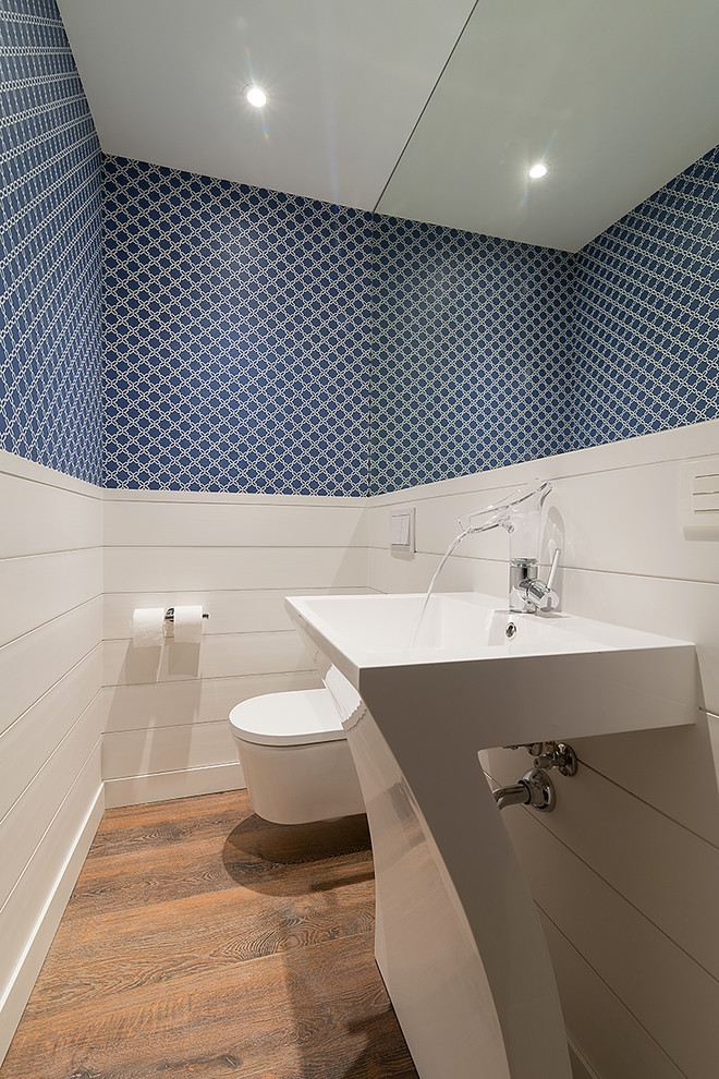 На фото: туалет в стиле неоклассика (современная классика) с инсталляцией, синими стенами, паркетным полом среднего тона и раковиной с пьедесталом с
