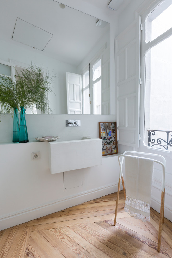 Ejemplo de aseo actual con paredes blancas, suelo de madera clara, lavabo suspendido y suelo beige