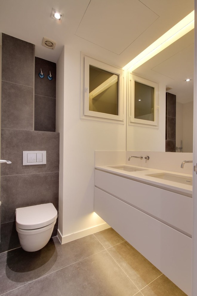 Cette photo montre un WC suspendu scandinave de taille moyenne avec un placard à porte plane, des portes de placard blanches, un lavabo intégré, un mur blanc, parquet clair et un sol marron.
