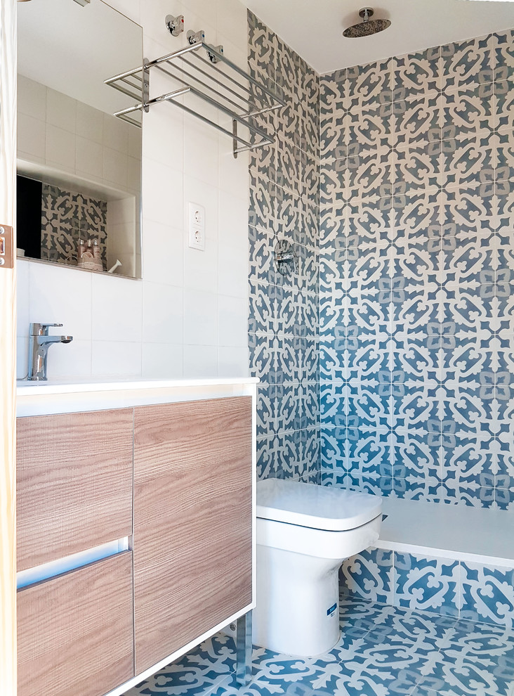 Inspiration for a small classic cloakroom in Barcelona with freestanding cabinets, light wood cabinets, a one-piece toilet, blue tiles, ceramic tiles, blue walls, ceramic flooring, a console sink, solid surface worktops, blue floors and white worktops.
