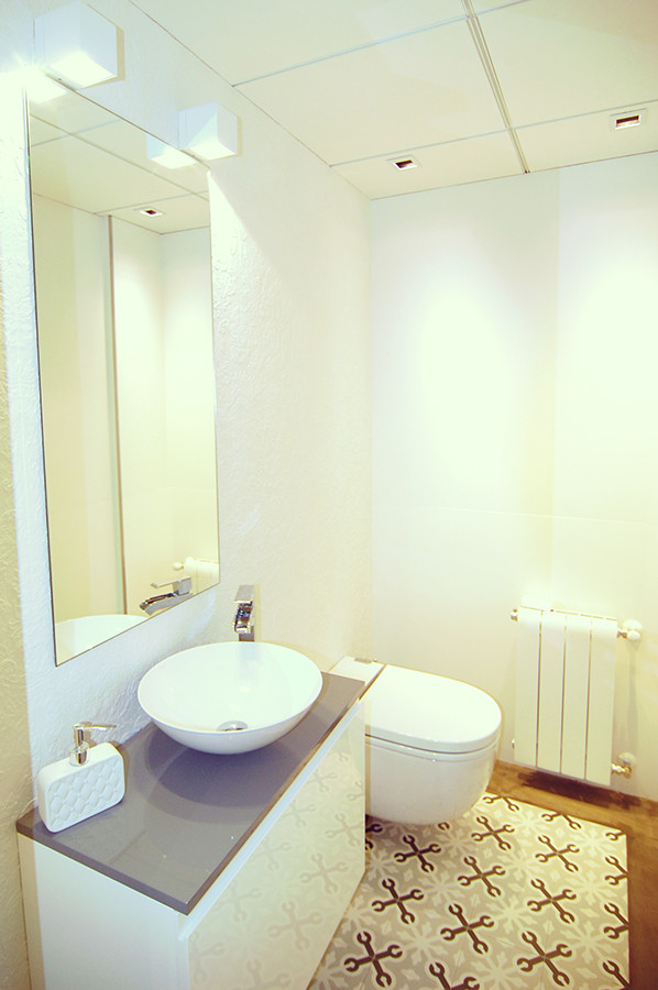 Idéer för att renovera ett litet minimalistiskt toalett, med släta luckor, vita skåp, en vägghängd toalettstol, vita väggar, mellanmörkt trägolv och ett fristående handfat
