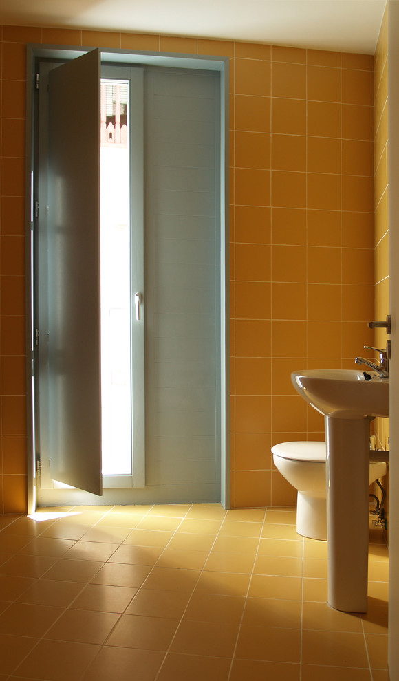 На фото: маленький туалет в скандинавском стиле с желтой плиткой, керамической плиткой, желтыми стенами, полом из керамической плитки, биде и раковиной с пьедесталом для на участке и в саду