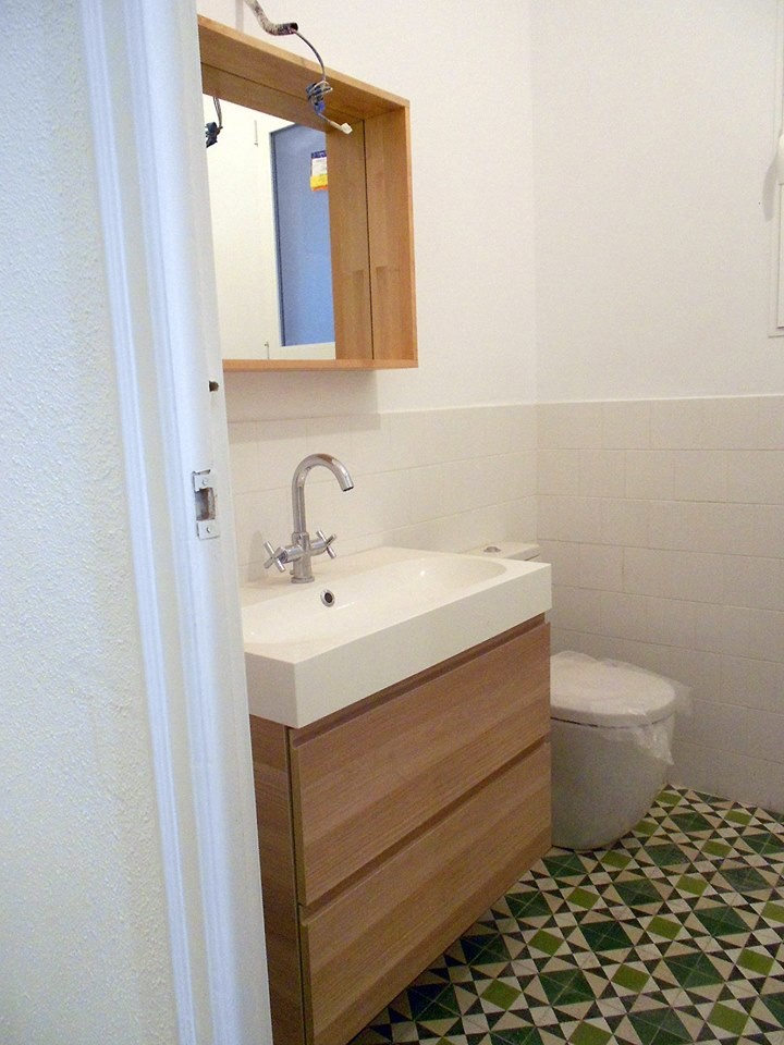 Kleine Nordische Gästetoilette mit flächenbündigen Schrankfronten, hellbraunen Holzschränken, Wandtoilette mit Spülkasten, weißer Wandfarbe und integriertem Waschbecken in Valencia